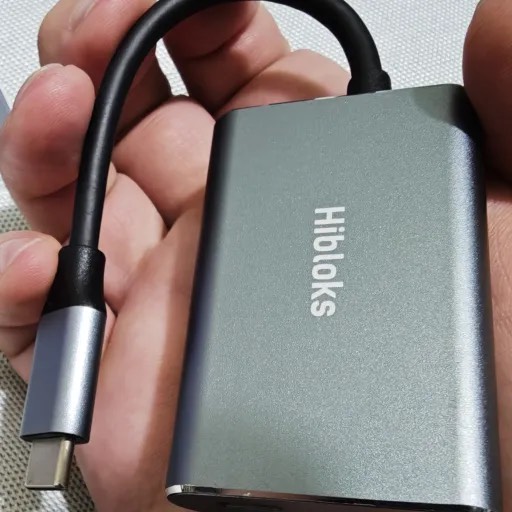 Hibloks HDMI-to-USB-C adapter held in one hand